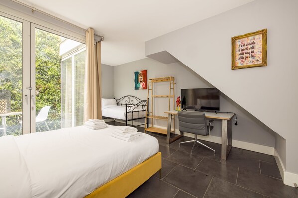 Une chambre à coucher avec un lit, un bureau, une chaise, un téléviseur et un tableau accroché au mur.