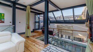A modern interior with a glass balustrade, a white sofa, and a view of the city through large windows.