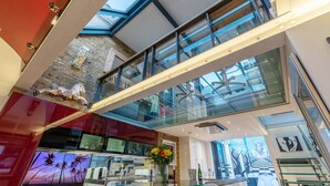 A modern interior with a glass ceiling, a staircase, and a dining area with a TV and flowers.