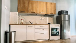 Una cucina moderna con mobili in legno, un frigorifero in acciaio inossidabile, un forno integrato e un cestino per i rifiuti.