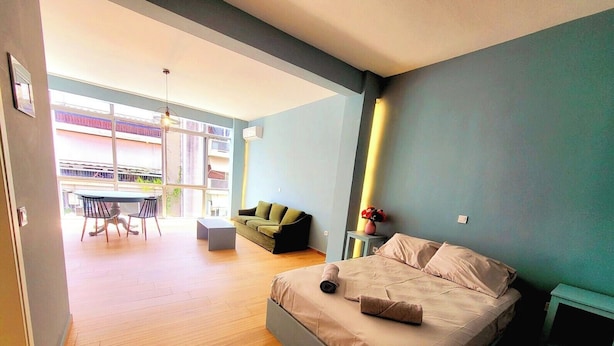 Una camera da letto moderna con un letto grande, un divano e un'area pranzo con tavolo e sedie.