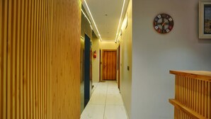 A hallway with wooden paneling, a clock, and a fire extinguisher.