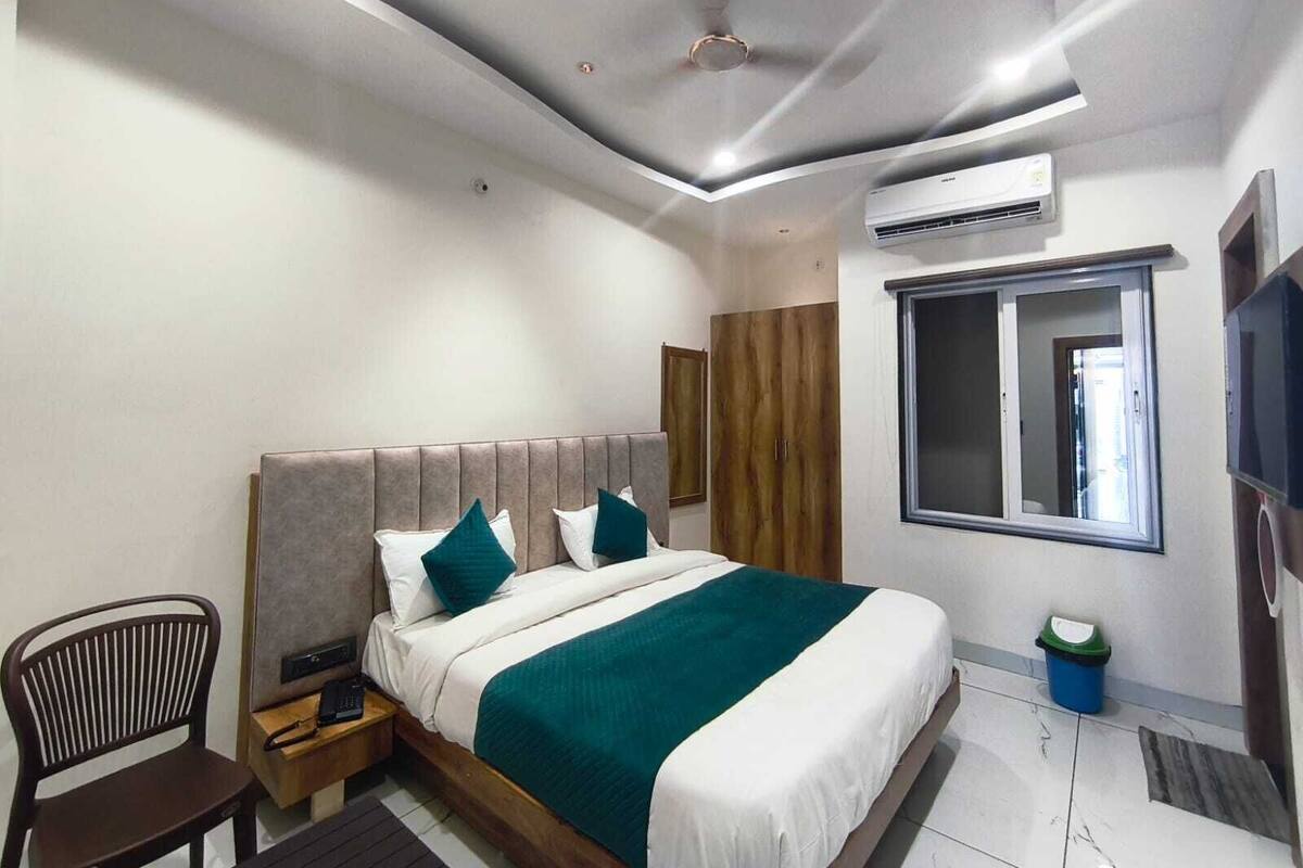 Un dormitorio moderno con cama, una silla, un equipo de aire acondicionado y una ventana.