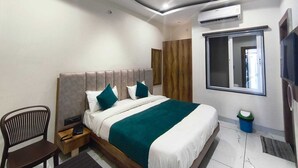 A modern bedroom with a bed, a chair, an air conditioning unit, and a window.