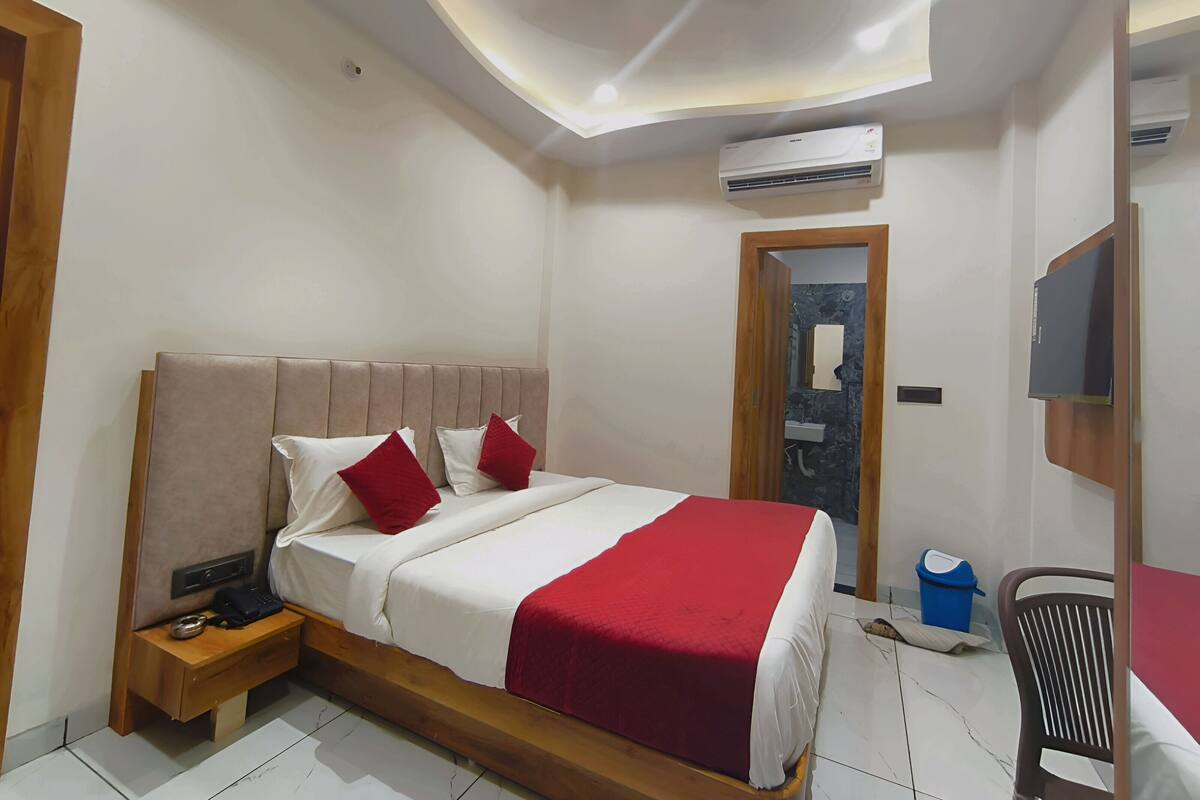 Un dormitorio con cama, mesita de noche y una silla de madera.