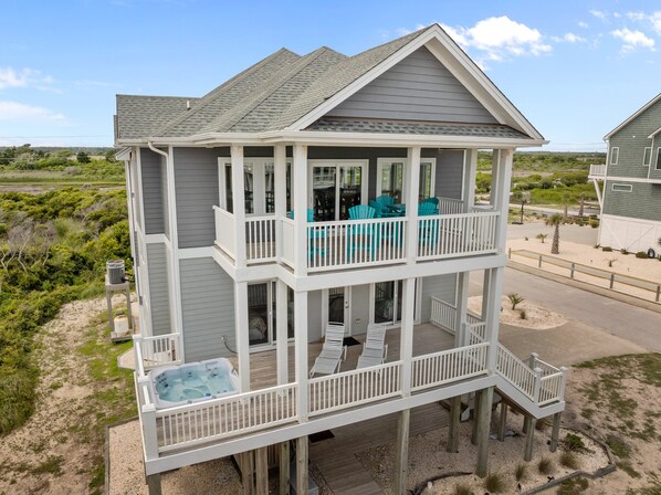 A two-story house with a balcony, a hot tub, and outdoor seating.