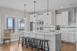 A modern kitchen with white cabinetry, a central island with bar stools, and pendant lighting.