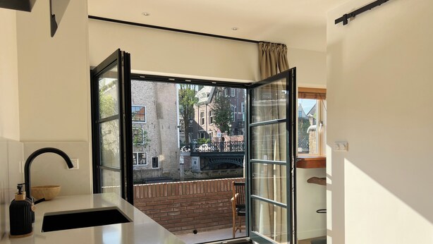 Eine moderne Küche mit einem großen Fenster, einer Spüle und einer Holzschüssel auf der Arbeitsplatte.