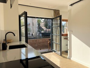 A modern kitchen with a large window, a sink, and a wooden bowl on the counter. - Maison Arrière (Dordrecht)