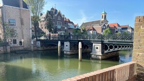 Ein Kanal mit Brücke, historischen Gebäuden und einer Ziegelmauer.