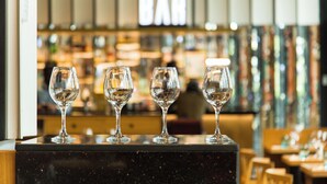 Un coin bar avec quatre verres à vin vides sur un comptoir en marbre noir.
