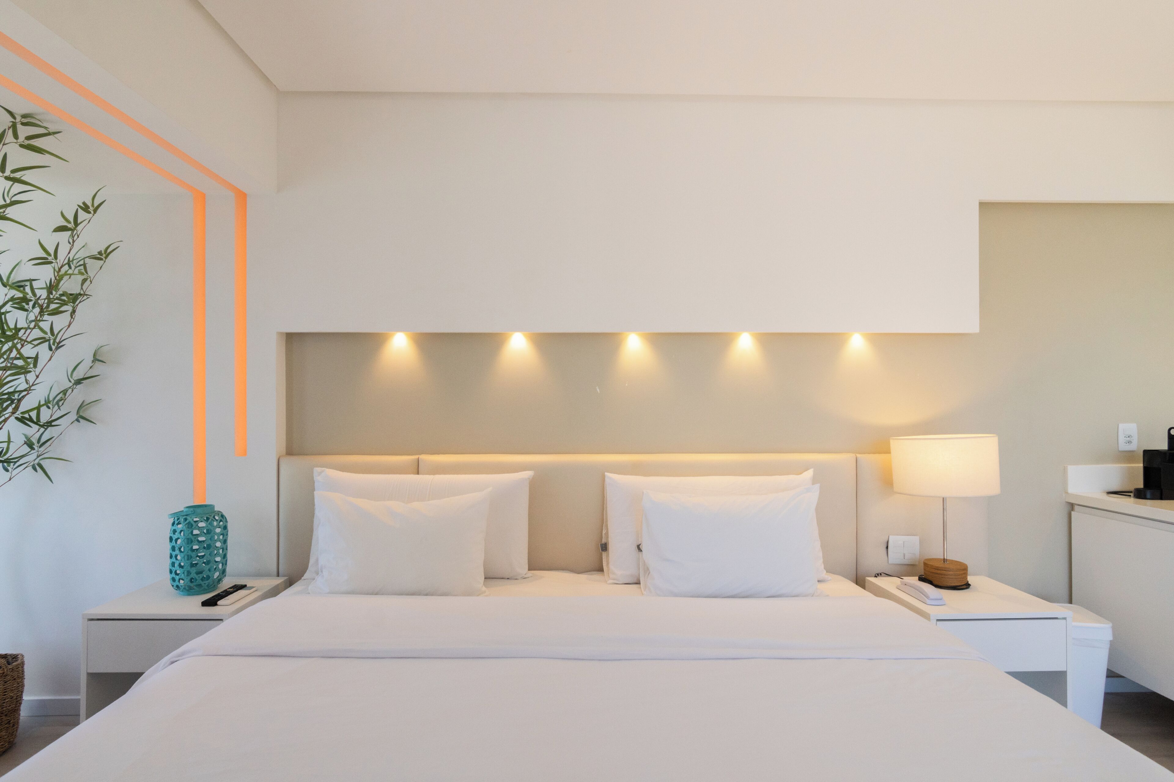 A hotel room with a bed, bedside tables, a lamp, and a wall-mounted light fixture.
