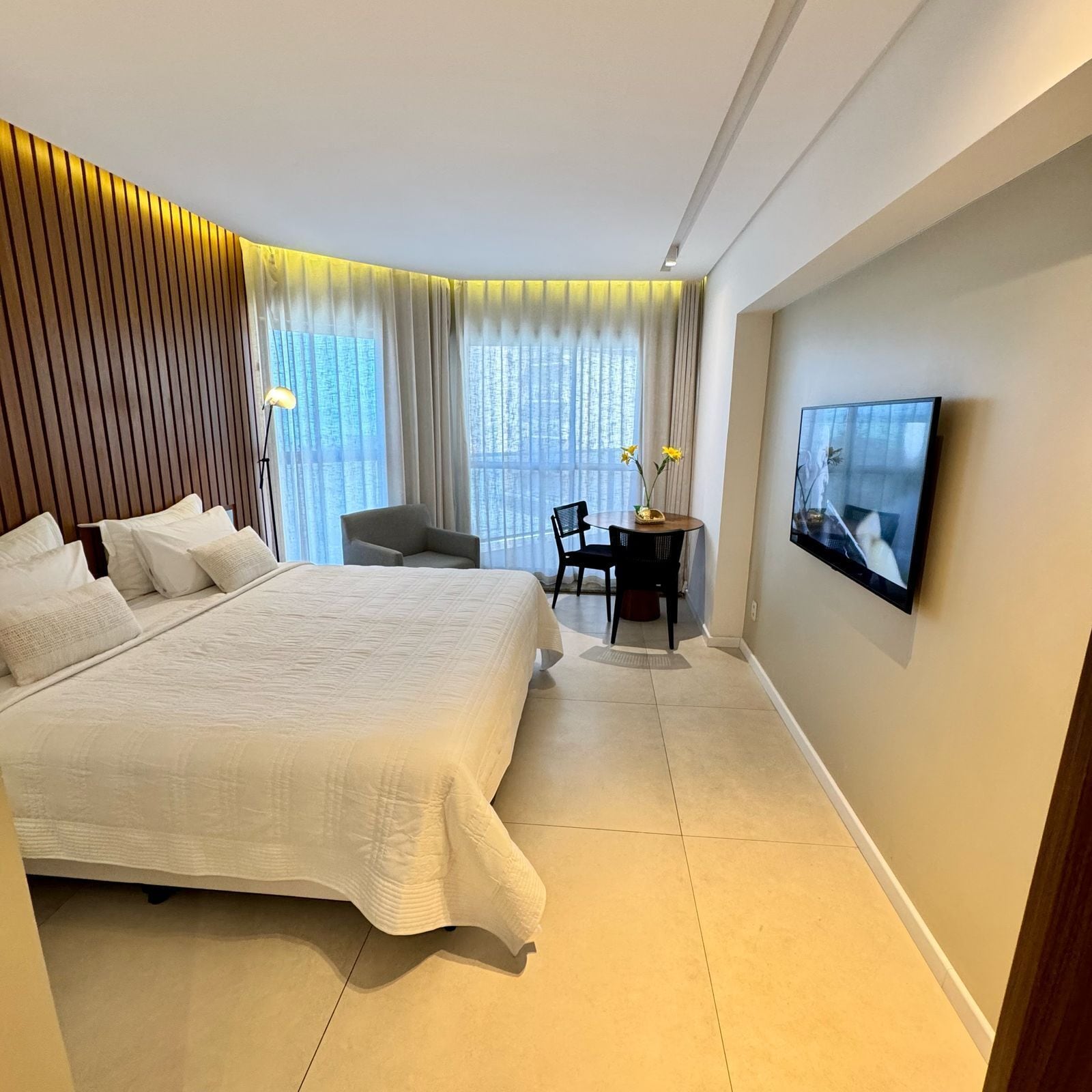 A modern hotel room with a large bed, a desk, and a TV.