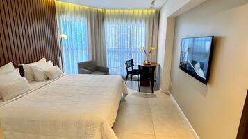 A modern hotel room with a large bed, a desk, and a TV.