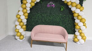 Een kamer met een bank en een decoratieve boog van witte en gouden ballonnen.