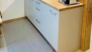 A compact kitchen with white cabinets, a wooden countertop, a Siemens microwave, and a coffee maker.