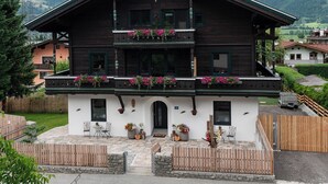 A two-story wooden building with balconies, a white facade, and flower boxes.