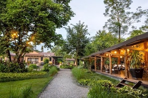 A garden pathway leading to a covered outdoor seating area with tables and chairs.