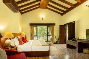 A bedroom with a large bed, a wooden ceiling, a television, and a window with curtains.