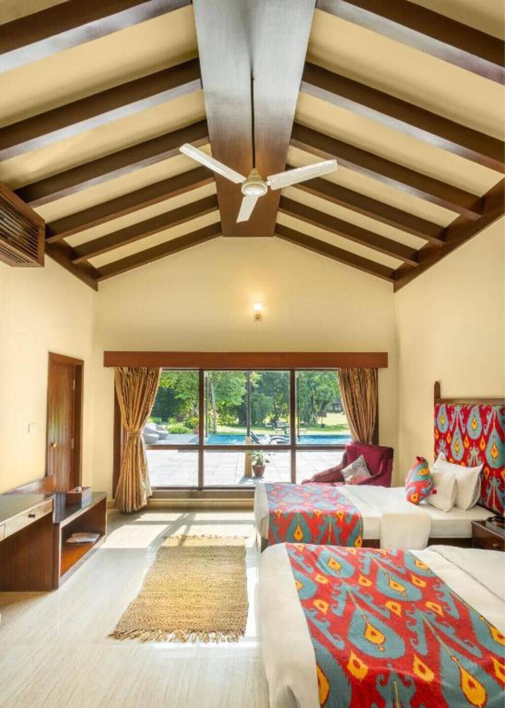Ein Hotelzimmer mit einem großen Bett, einem Einzelbett, einem Schreibtisch und einem Fenster mit Blick ins Freie.