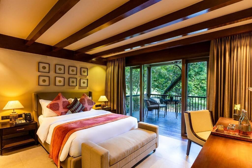 Une chambre d’hôtel comprenant un lit, des tables de chevet, un bureau avec une chaise et un balcon avec une table et des chaises.