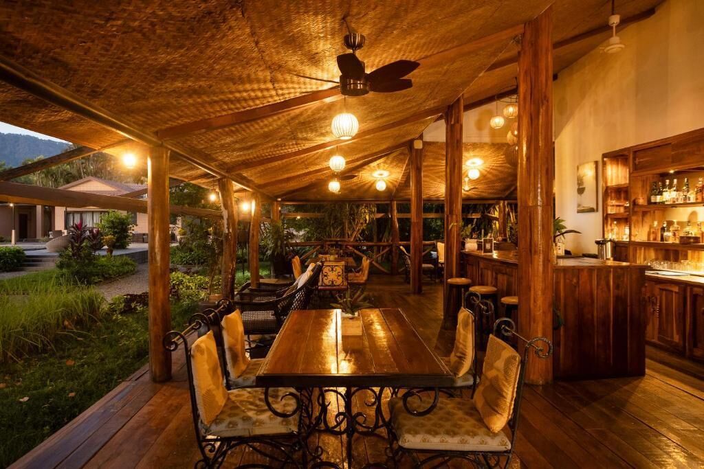 Un espace de restauration en plein air avec des tables et des chaises en bois, un bar et un ventilateur de plafond.