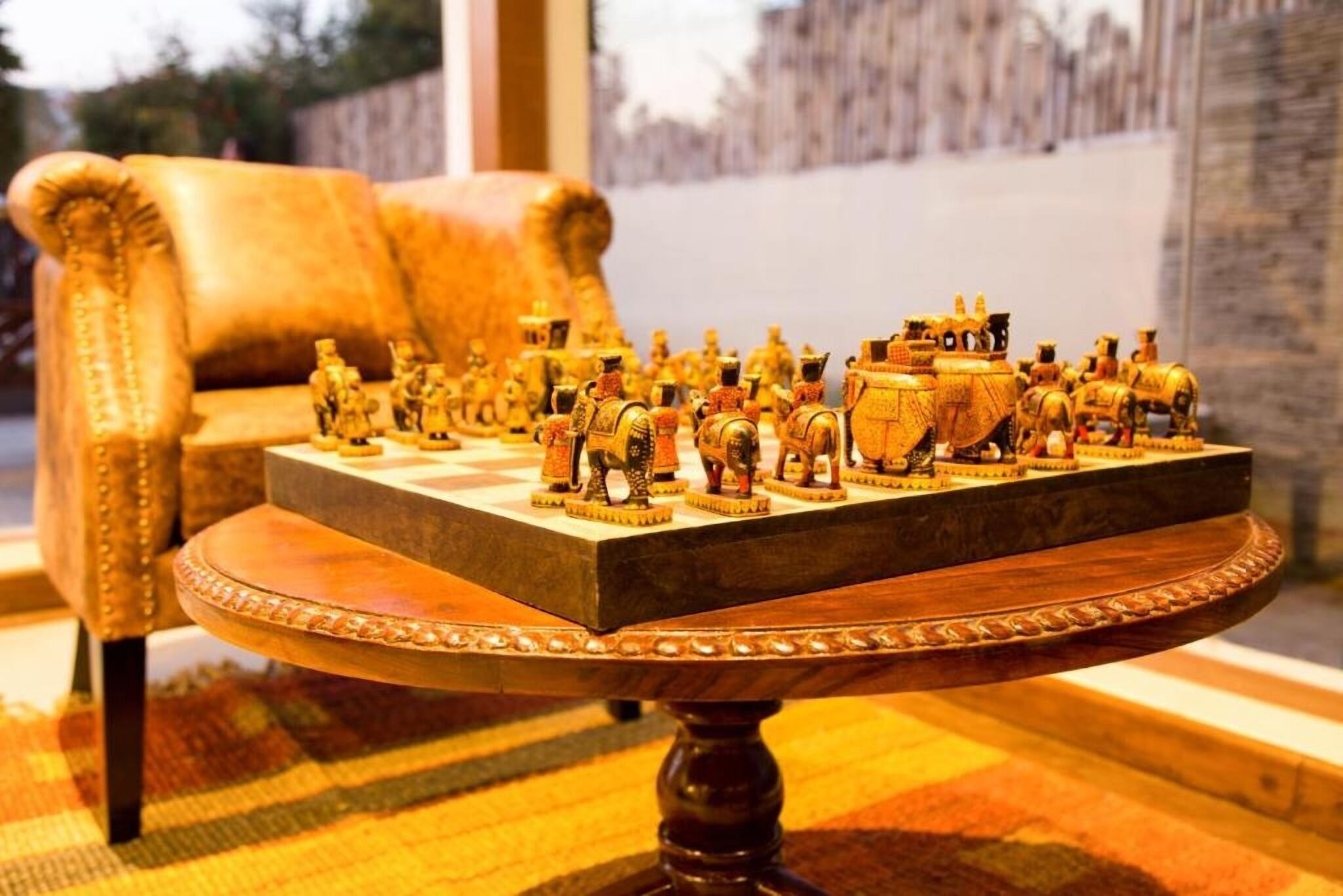 A chessboard with figurines on a table in a room with a sofa and a window.