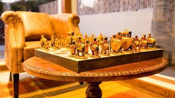 A chessboard with figurines on a table in a room with a sofa and a window.