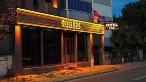 A hotel with a prominent sign, large windows, and a flag. - Akçay Otel Ege (Edremit)