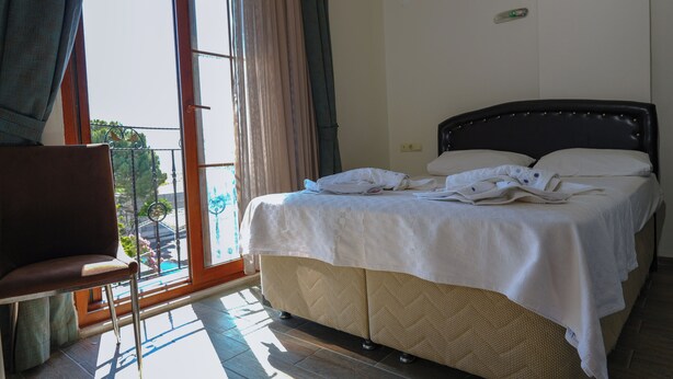 A hotel room with a bed, a chair, and a view of the outdoors. - Akçay Otel Ege (Edremit)