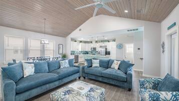 A spacious living room with two blue sofas, a coffee table, and a ceiling fan.