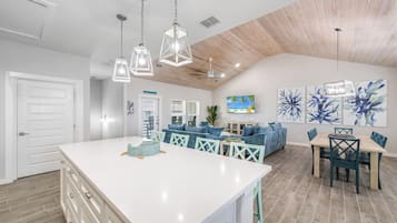 A spacious kitchen with a large island, wooden ceiling, and pendant lighting.