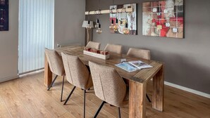Un coin repas avec une table en bois, six chaises et un magazine posé sur la table.