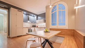 A modern kitchen with a central island, wooden flooring, and a large window with a view. - Sweett | Sepulveda 2C (Barcelona)