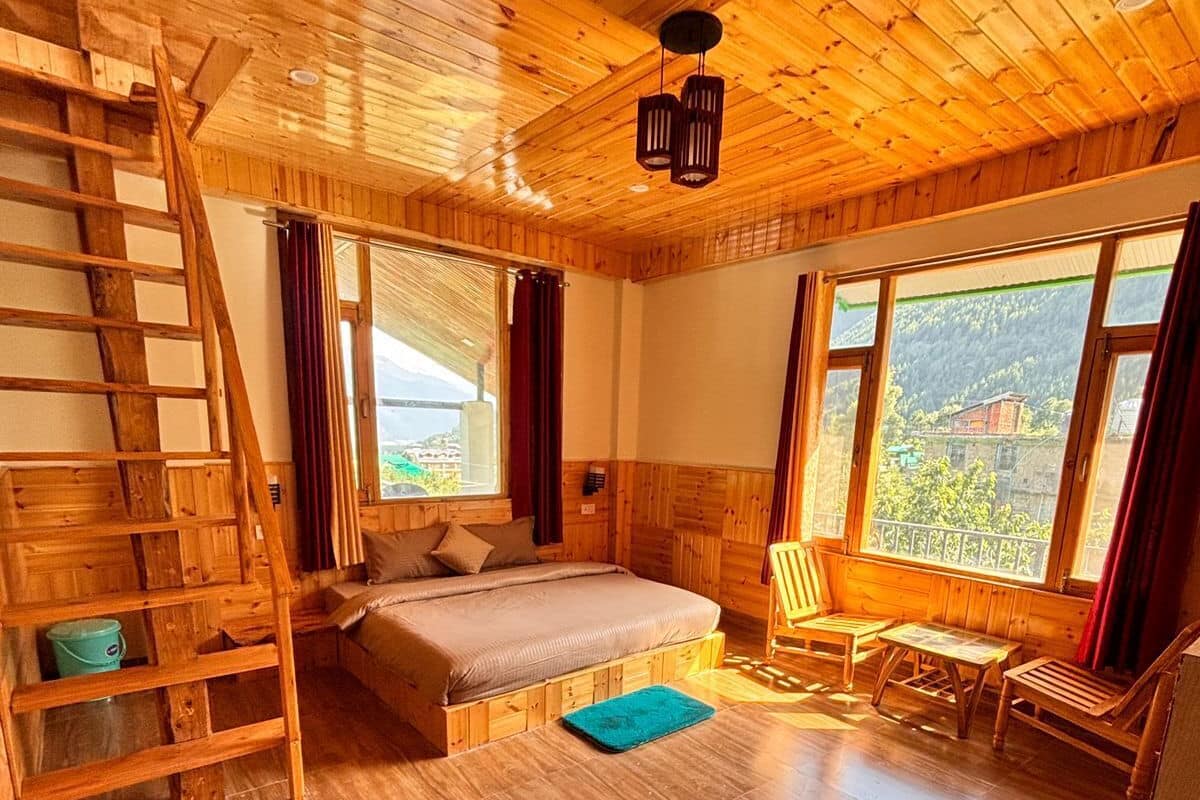 A wooden cabin with a loft bed, a ladder, a small table, and a chair.