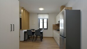 Una cocina moderna con comedor, que incluye un refrigerador, armarios y una mesa con sillas.