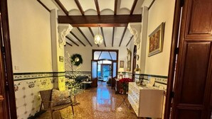 A hallway with a polished floor, a wooden bench, a table with a white cloth, and a door on the right. - HOLIDAY COTTAGE VILLALONGA RURAL (Vilallonga)