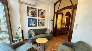A cozy living room with a sofa, two armchairs, and a small round table. There are framed pictures on the wall and a staircase leading to another room. - HOLIDAY COTTAGE VILLALONGA RURAL (Vilallonga)
