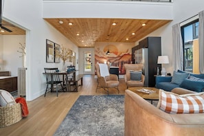 A modern living space with a dining area, a sofa, and a kitchen.