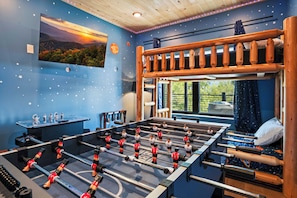 A room with a foosball table, a window with a view, and a starry wall design. - Private Indoor Pool, Spacious Deck, Mountain Views (Sevierville)