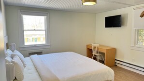 Een slaapkamer met een bed, een bureau, een stoel, een televisie en een raam.
