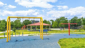 A playground with a red and yellow swing set, a blue slide, and a red climbing structure. - 3 Mi to National Mall: Artsy DC Condo Near Metro! (Washington)