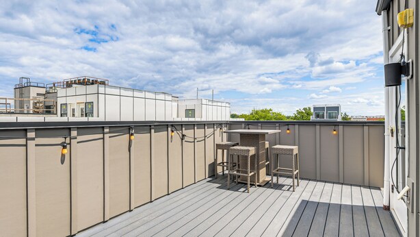 A rooftop terrace with a wooden deck, outdoor seating, and a view of the city skyline. - 3 Mi to National Mall: Artsy DC Condo Near Metro! (Washington)