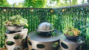 A barbecue grill with a George Foreman lid, surrounded by potted plants on a round table with cut-out designs. - Modern Home Between Seattle, Tacoma & SEA Airport (Renton)