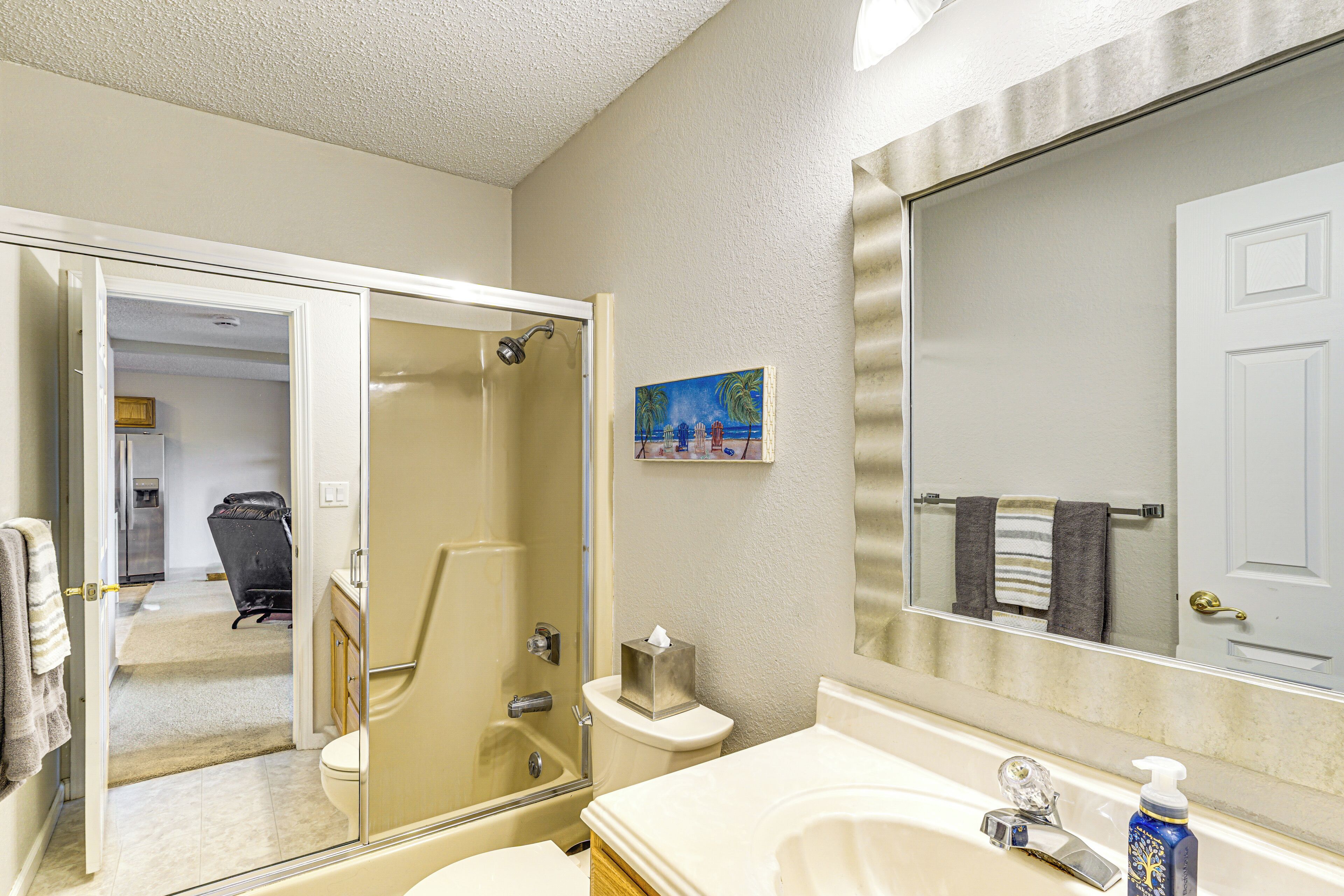 A bathroom with a glass-enclosed shower, a toilet, a sink with a mirror, and a towel rack.