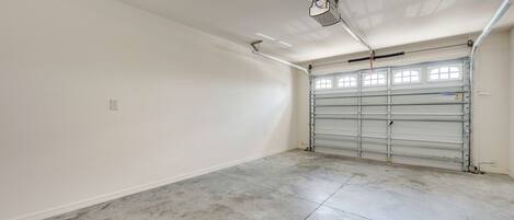 Un garage propre et vide, doté d’une porte métallique, d’un éclairage fluorescent et d’un ventilateur de plafond.