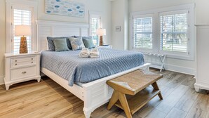 A bedroom with a bed, nightstands, a bench, and large windows. - Walk to the Waves: Coastal Kure Beach Retreat (Kure Beach)