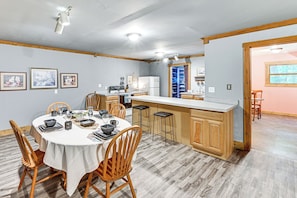 Una cocina moderna con armarios de madera, una isla central y un comedor con una mesa redonda y sillas.