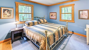 Une chambre à coucher avec un lit, une table de chevet et deux fenêtres.