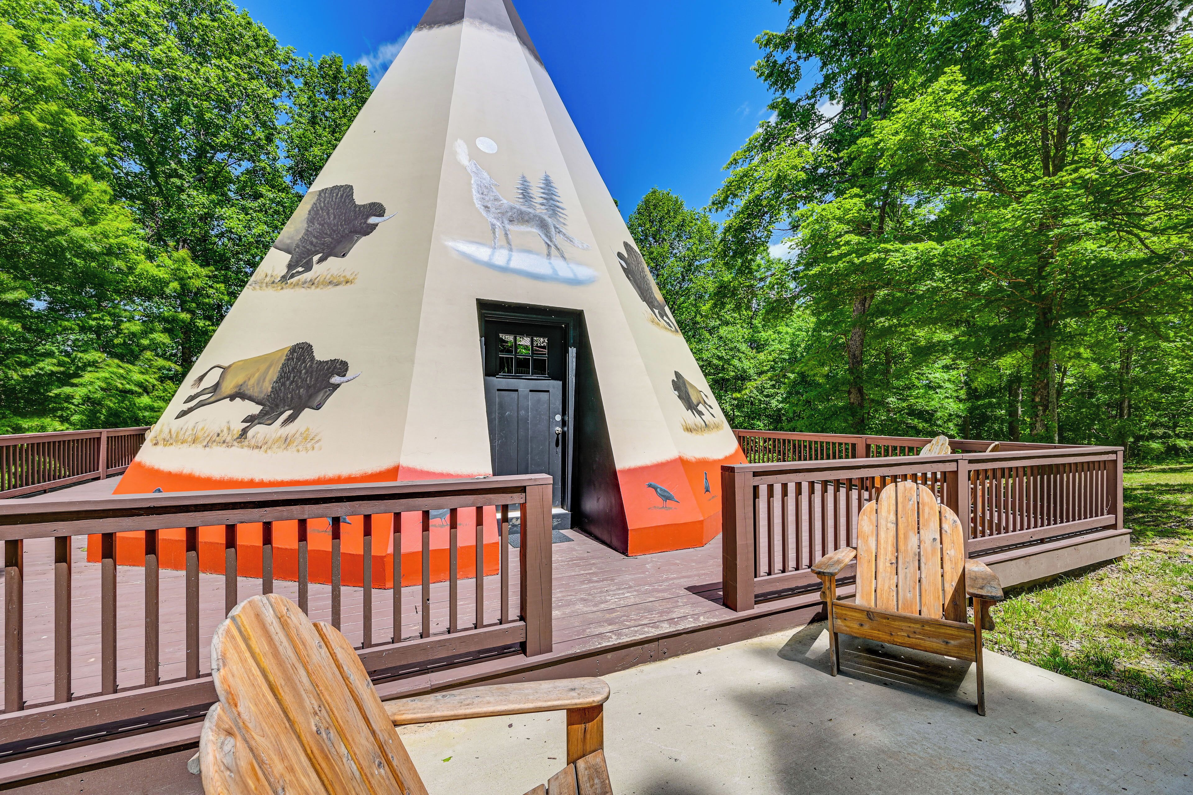 A conical structure with wildlife murals, a door, and wooden benches.